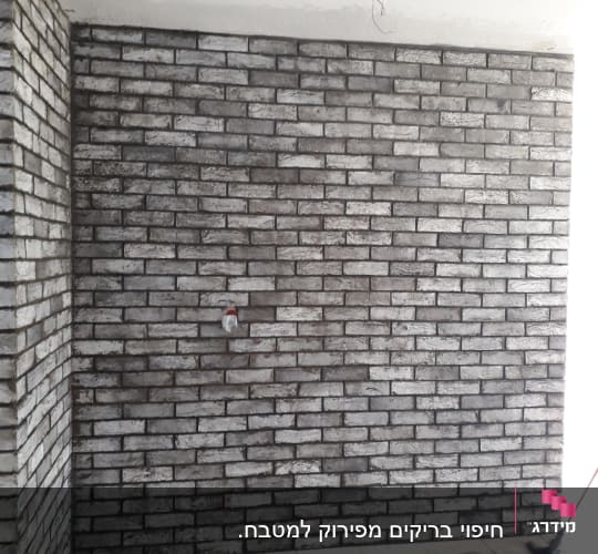 קיר לבנים חשוף עם חוטי חשמל גלויים
